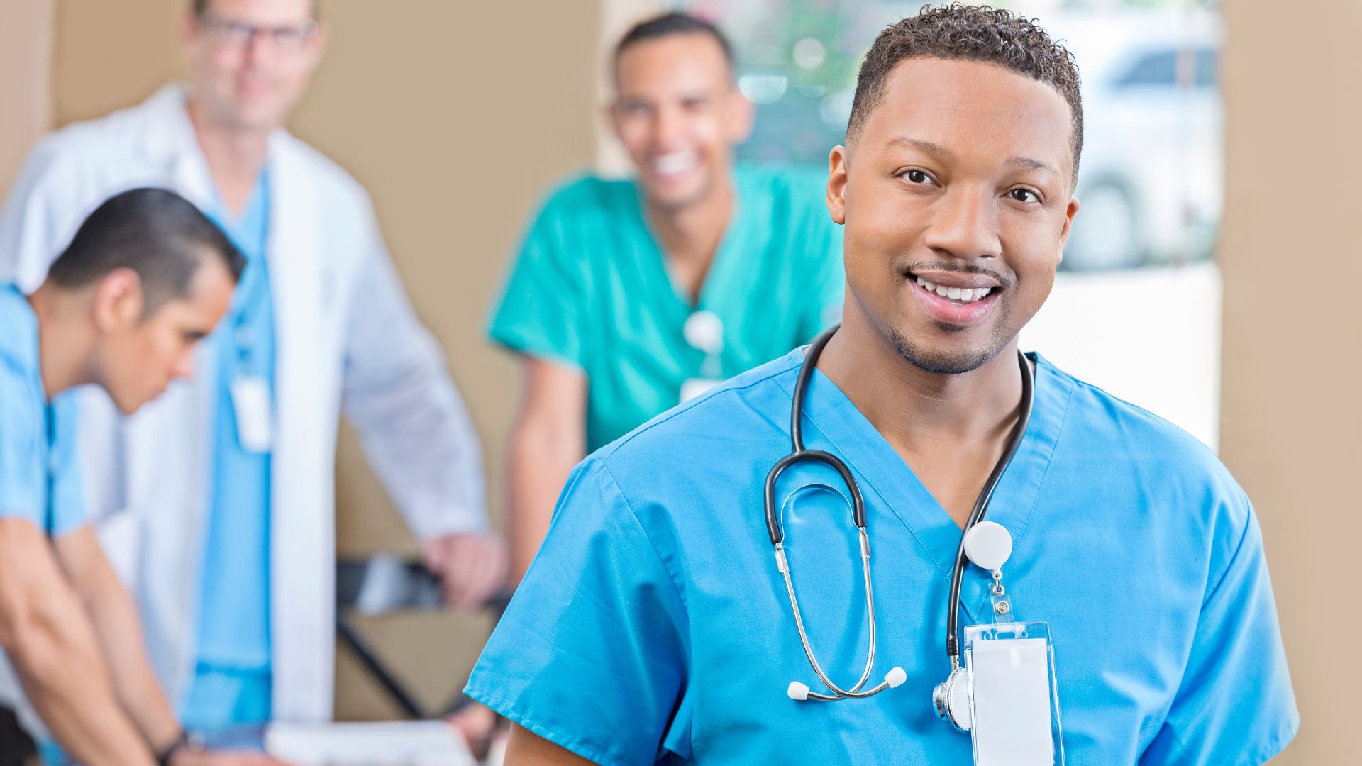 Professionnel de santé en blouse bleue avec un stéthoscope, avec trois collègues en arrière-plan